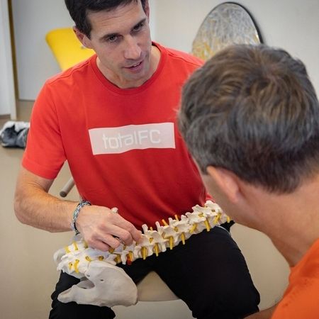Physiotherapeut erklärt einem Patienten die Wirbelsäule