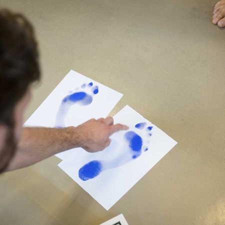 Therapeut erklärt Druckpunkte eines Fußes mithilfe eines Abdruckes