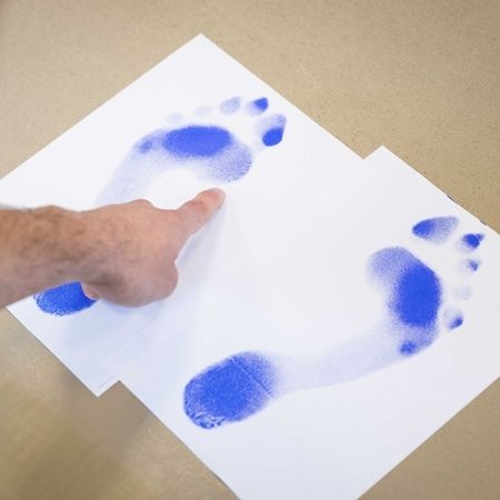 Therapeut erklärt Druckpunkte eines Fußes mithilfe eines Abdruckes