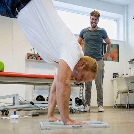 Patient steht auf seinen Händen unter Aufsicht