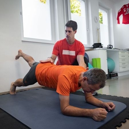 Patient liegt in einer Planke und hebt sein linkes Bein