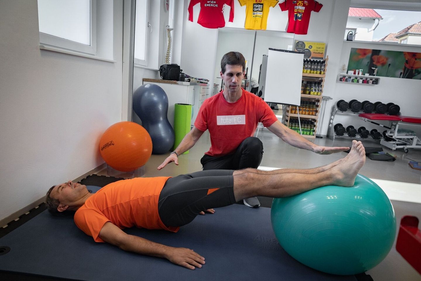 Physiotherapeut überprüft die Balance eines Patienten mithilfe eines Gymnastikballs