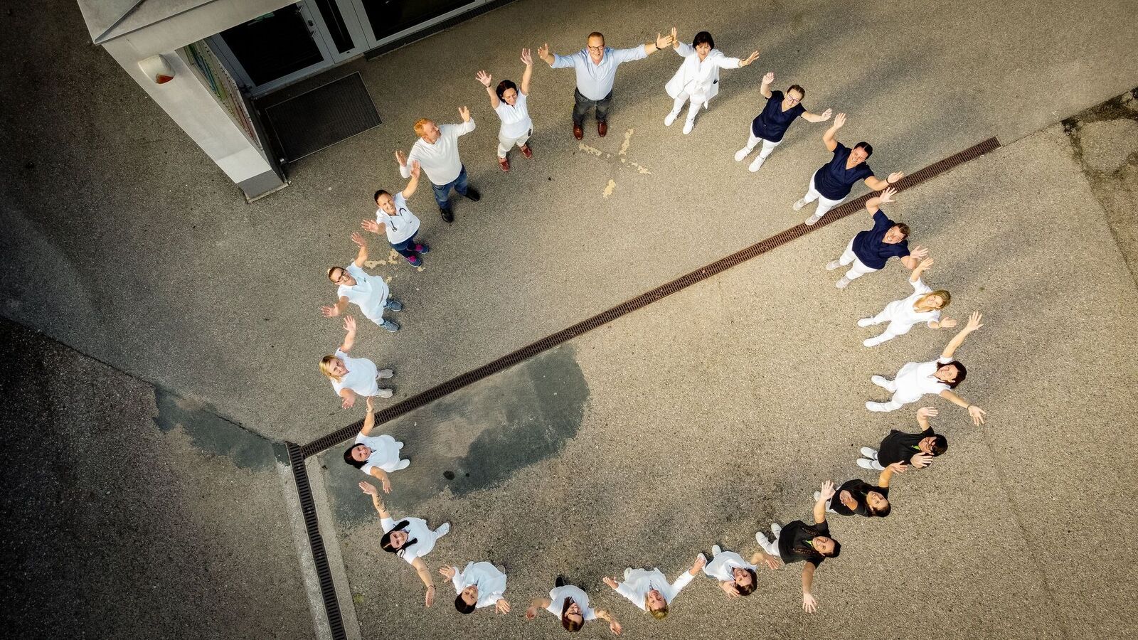 In einer Kreisform stehende Mitarbeiter werden von oben fotografiert